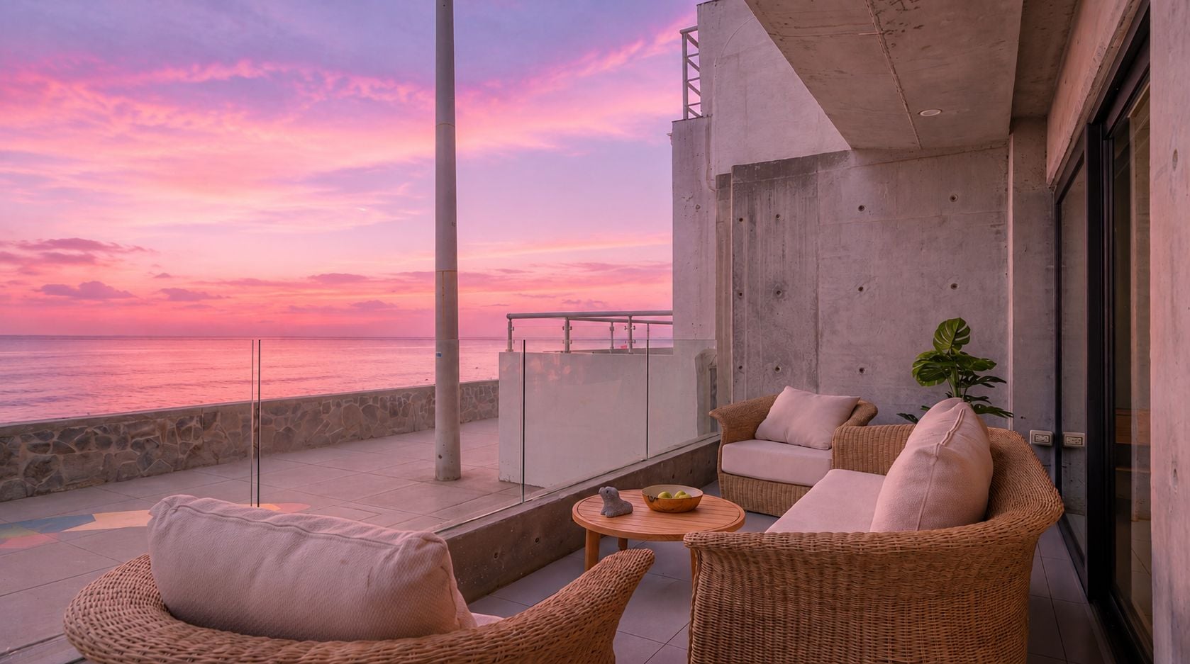 Ein Balkon mit Korbmöbeln, einem kleinen Tisch mit einer Schale und einem Topf mit Pflanze.