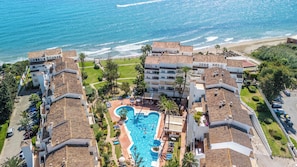 A resort with a central swimming pool, beachfront views, and terracotta-roofed buildings. - Marbella Playa Real | Pool & Sea View | 2 Bedrooms (Marbella)