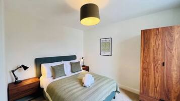 Una camera da letto con un letto, lampade da comodino, una lampada a parete, un quadro incorniciato e un armadio in legno.