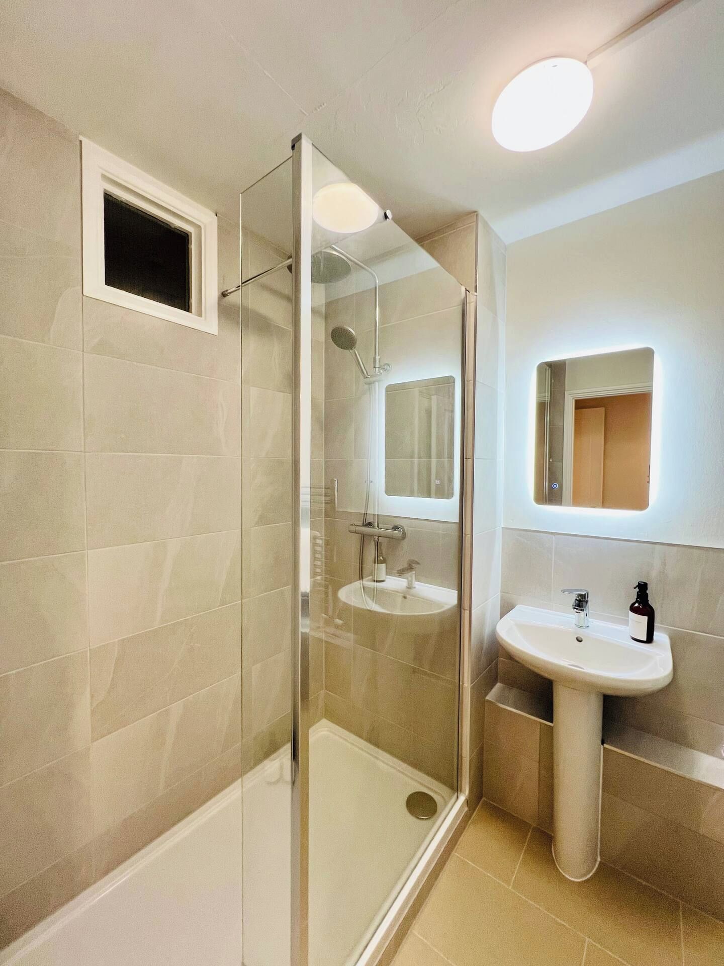 A modern bathroom with a glass-enclosed shower, a sink, and a mirror.