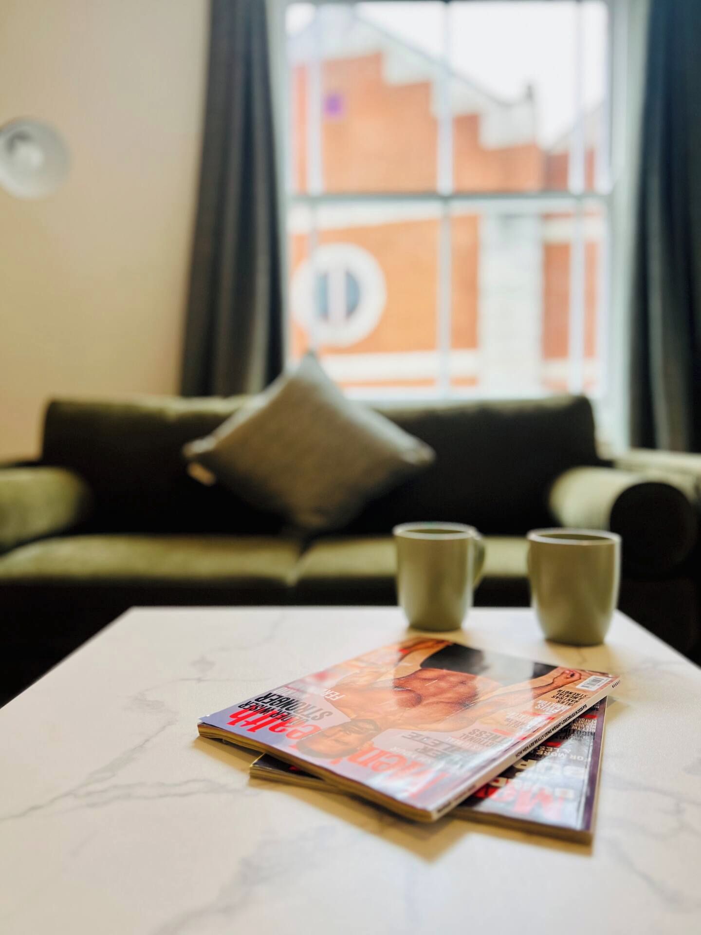 A magazine on a table with a sofa and two cups in the background.