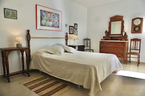 A bedroom with a bed, bedside tables, a dresser, a chair, a mirror, and a clock on the wall.