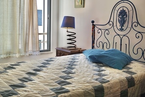 A bed with a quilt, a lamp, and a decorative headboard.
