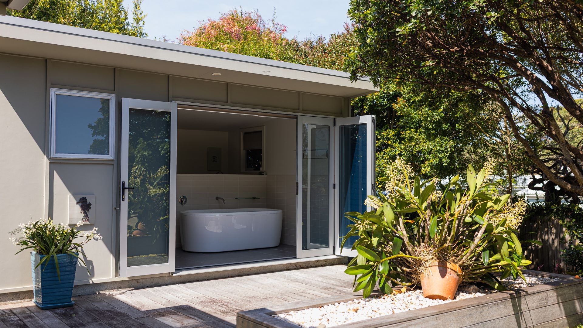 Una casa moderna con un gran ventanal que da a un baño espacioso con bañera y ducha.
