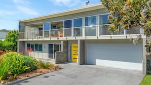 Una moderna casa a due piani con un balcone, un garage e un giardino curato.