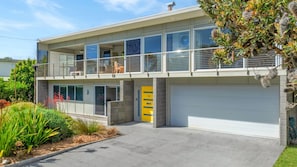 Ein modernes, zweigeschossiges Haus mit Balkon, Garage und einem gepflegten Garten.