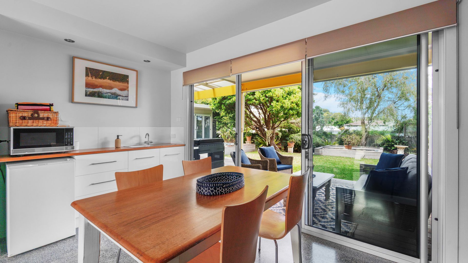 A modern kitchen with a dining area, sliding glass doors leading to a backyard with outdoor furniture.