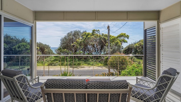 Un balcone con vista sul mare, un tavolo e due sedie.