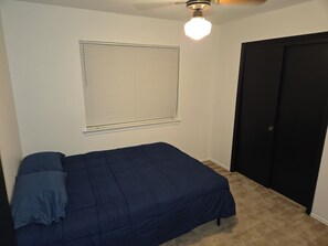 A bedroom with a bed, a window with blinds, a ceiling fan, and a door. - Beautiful Austin Home | Spacious, Furnished & Comfortable (Austin)