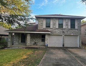 A two-story house with a garage, a covered porch, and a small front yard. - Beautiful Austin Home | Spacious, Furnished & Comfortable (Austin)