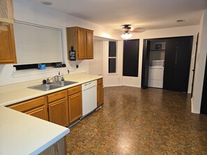 A kitchen with wooden cabinets, a dishwasher, a sink, and a ceiling fan. - Beautiful Austin Home | Spacious, Furnished & Comfortable (Austin)