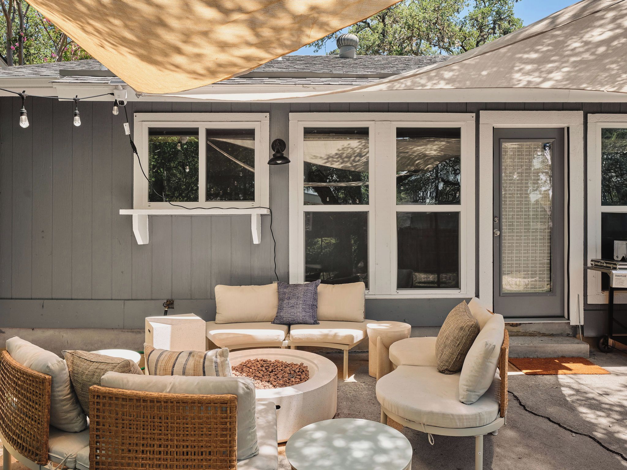 Un espace extérieur aménagé en terrasse, comprenant un coin salon avec un canapé, des fauteuils et une table ronde.