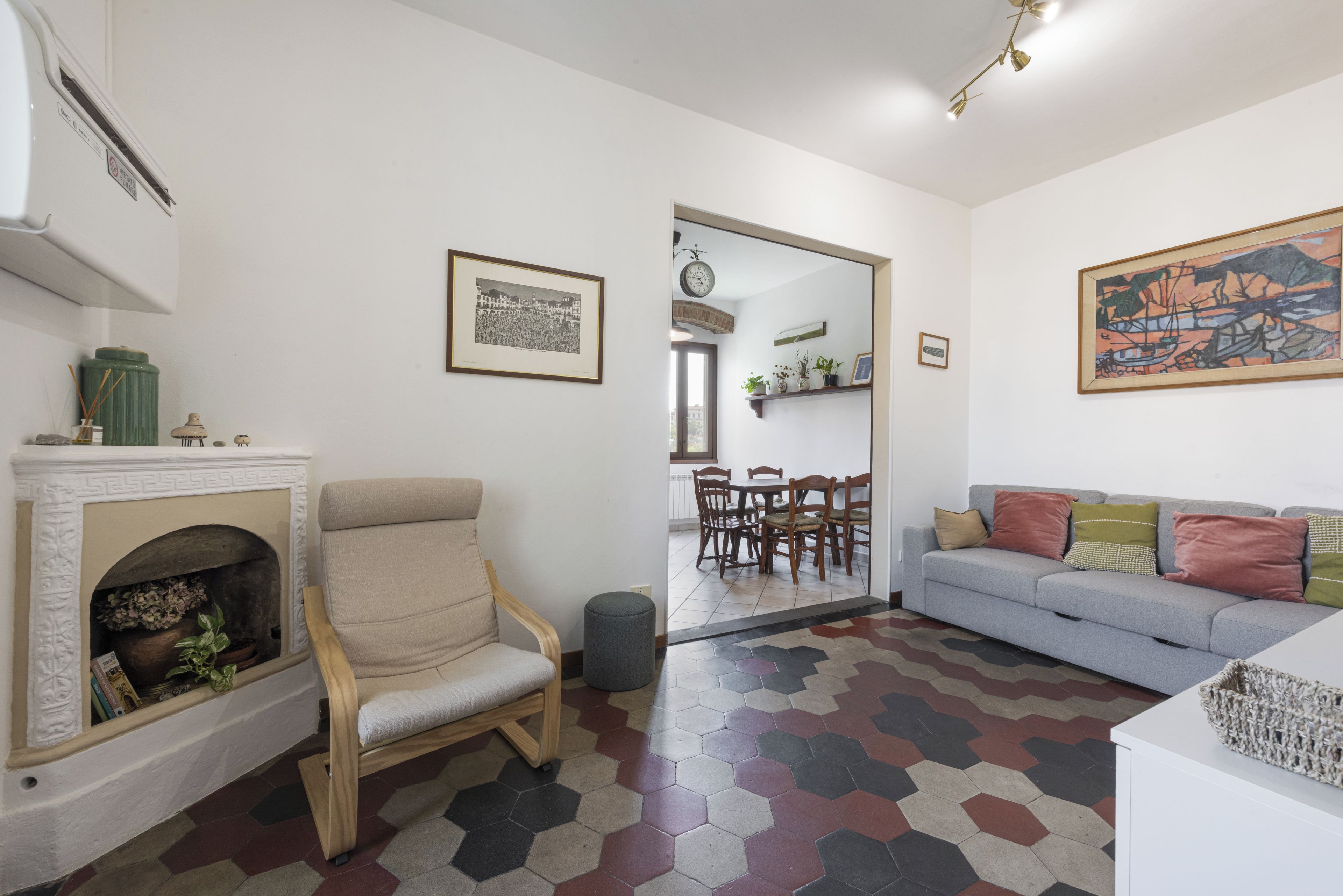 Una sala de estar con chimenea, un sofá, una mesa de comedor con sillas y un pasillo que lleva a otra habitación.