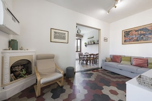 Una sala de estar con chimenea, un sofá, una mesa de comedor con sillas y un pasillo que lleva a otra habitación.