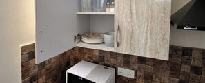 A kitchen with a white refrigerator, a white cabinet with a marble-like finish, and a tiled backsplash.