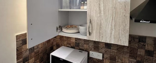A kitchen with a white refrigerator, a white cabinet with a marble-like finish, and a tiled backsplash.