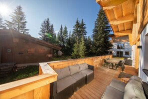 A wooden deck with a sofa, a table, and chairs. - Superb 9-bedroom chalet in alpine Zillertal for your getaway or wintersports (Hochkrimml)