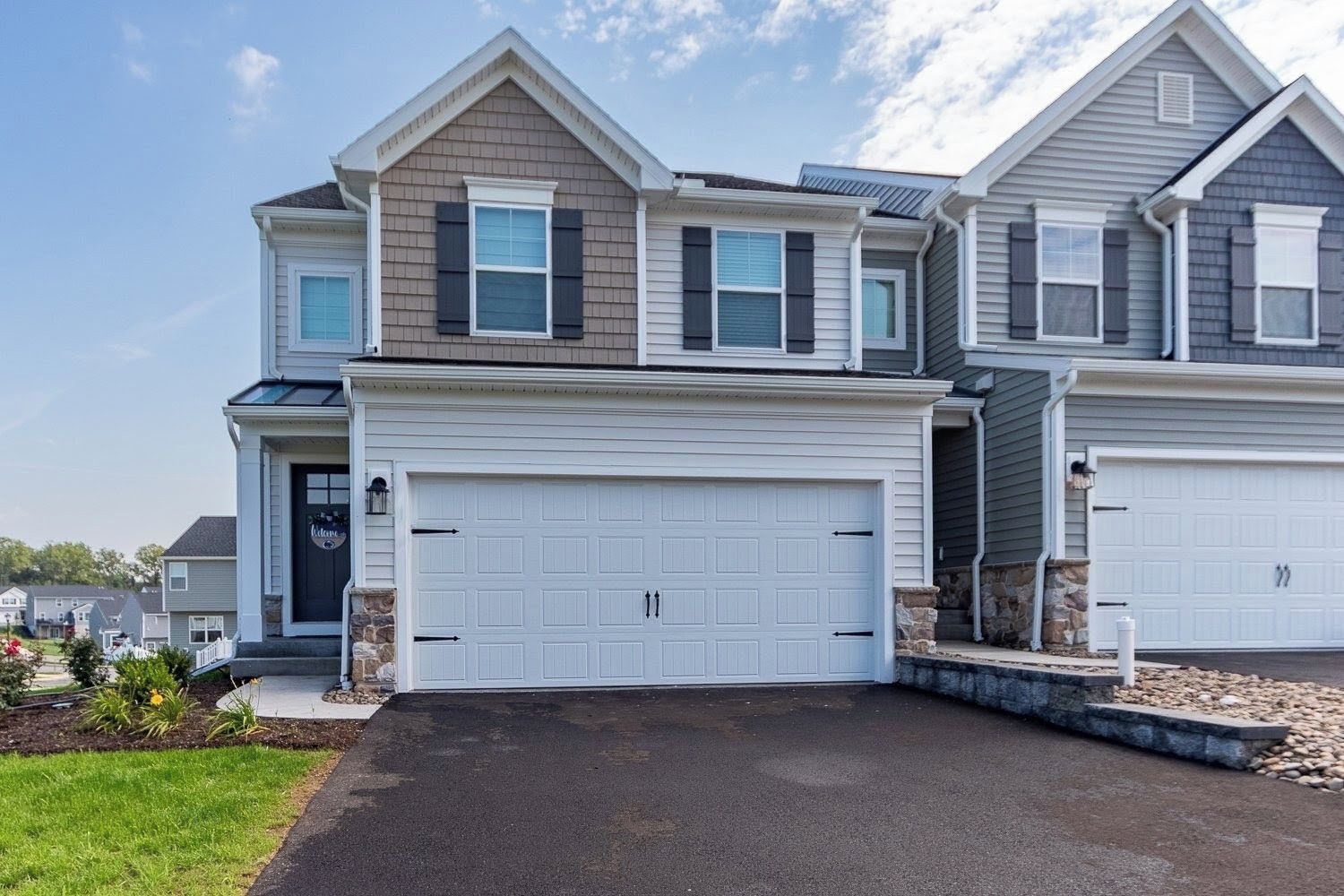 A two-story residential building with a large garage and a landscaped front yard.
