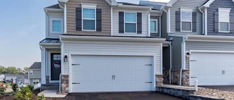 A two-story residential building with a large garage and a landscaped front yard.