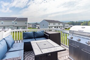 Un patio al aire libre con una parrilla, zona de estar y vistas a edificios residenciales.