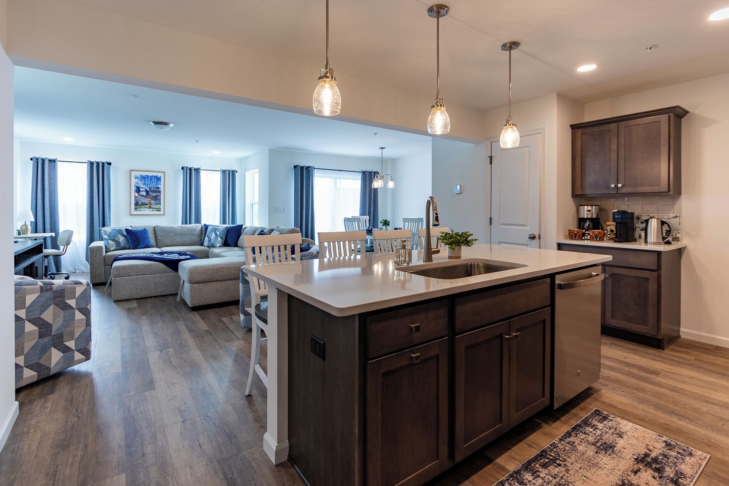 A modern kitchen with a central island, dark cabinetry, and pendant lighting.