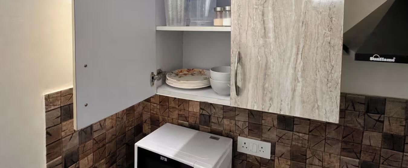 Een keuken met een witte koelkast, een wit kastje met een marmerlook afwerking en een betegelde achterwand.