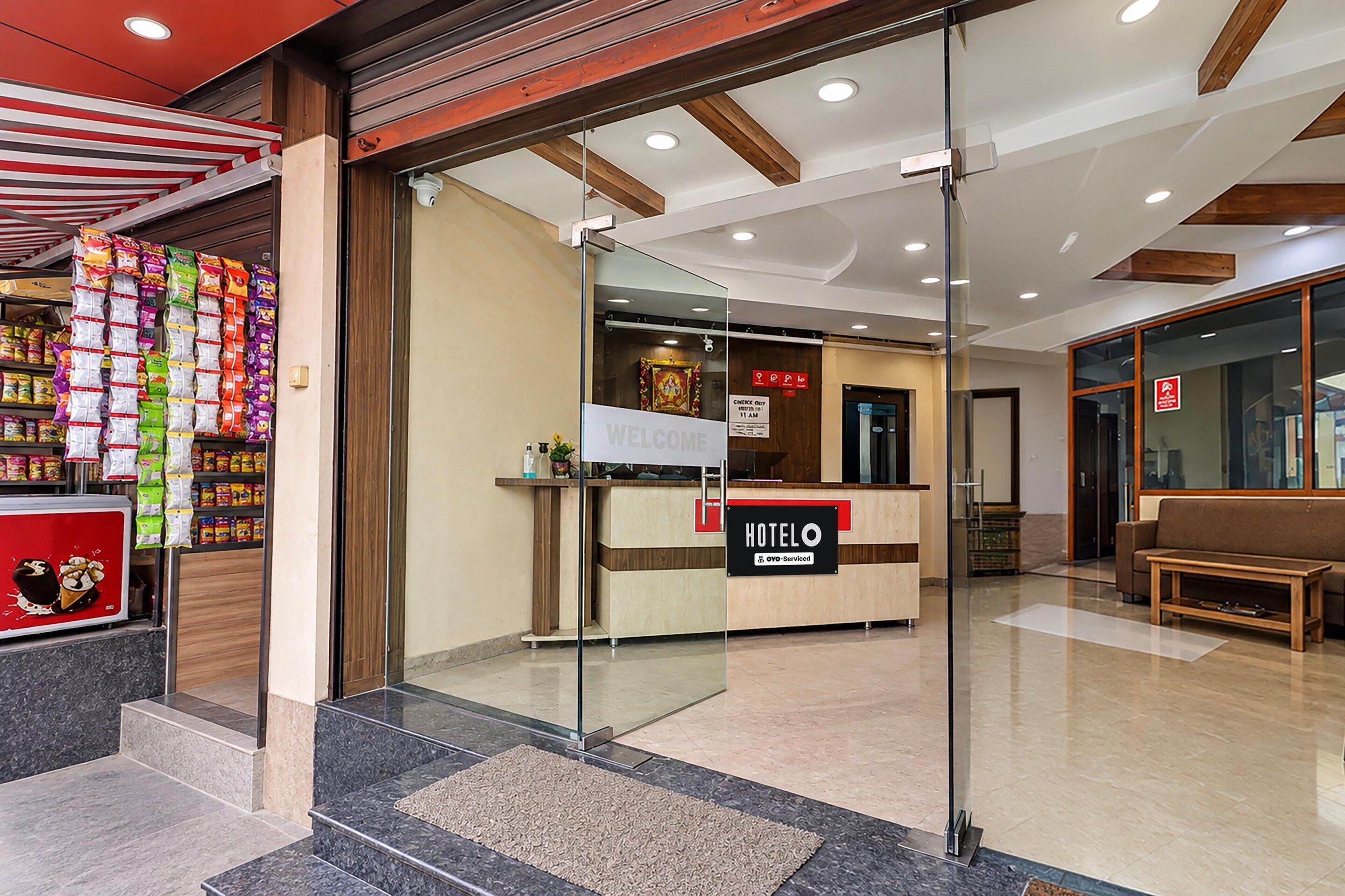 A hotel reception area with a reception desk, a sign indicating 'HOTELO' and 'OYO-Serviced', and a wall with a 'WELCOME' sign.