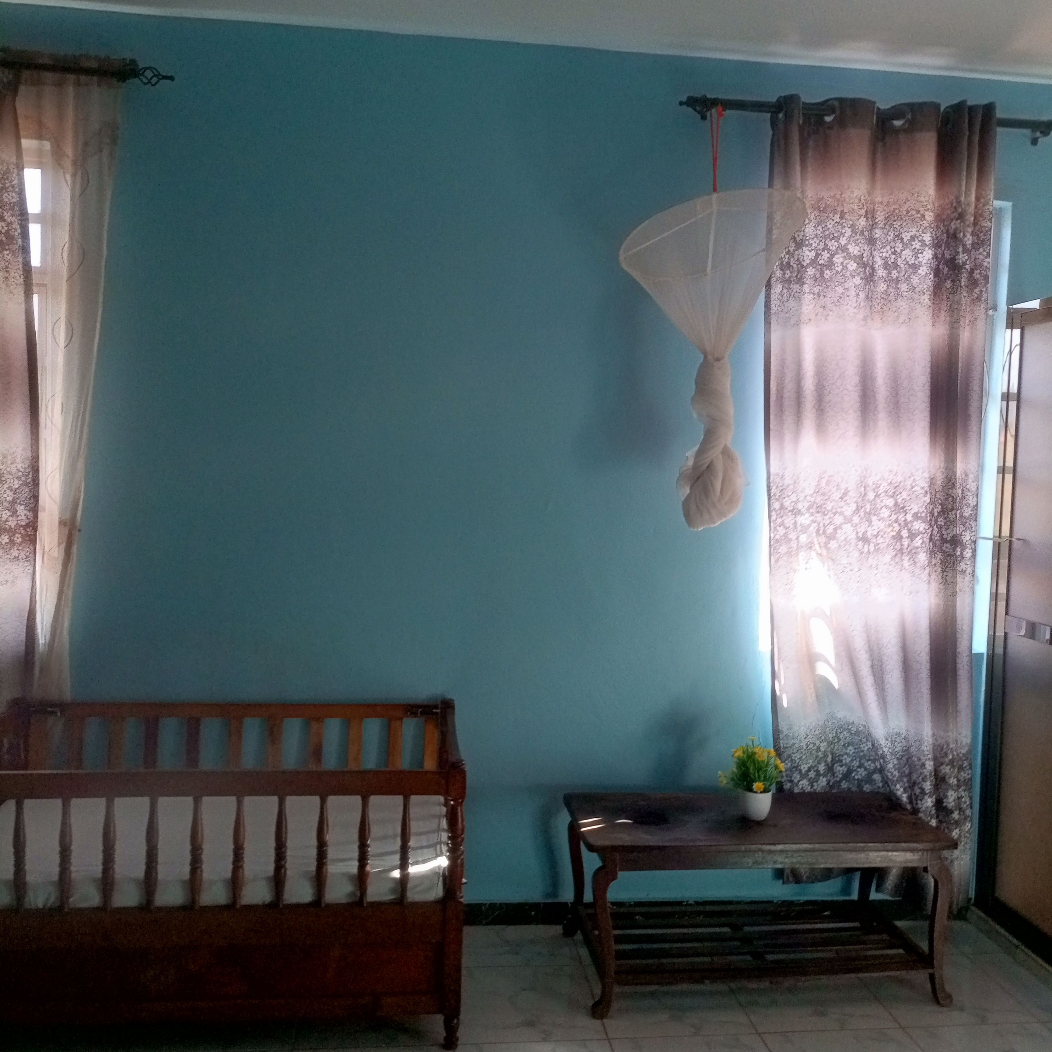 A room with a wooden bench, a small table with a plant, and a hanging light fixture.