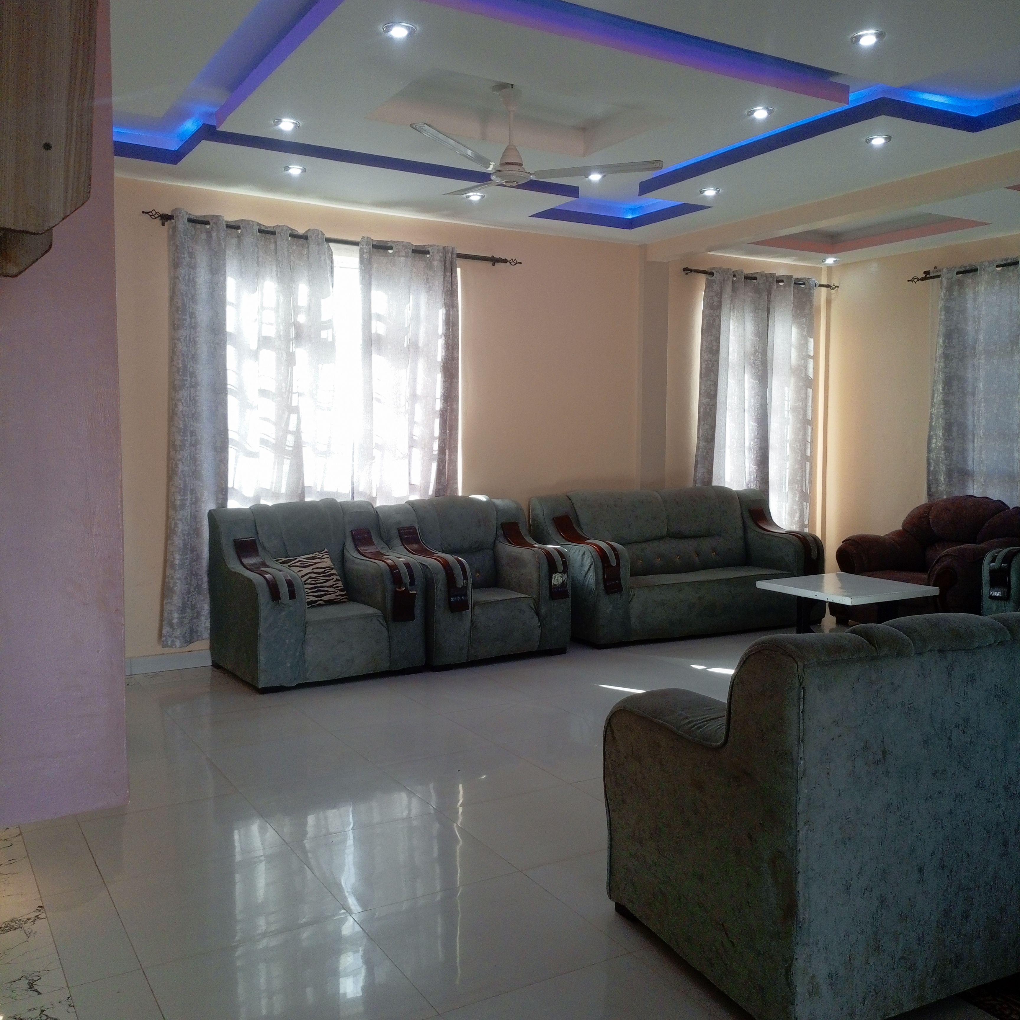 A living room with a sectional sofa, a single armchair, a small table, and a ceiling fan.