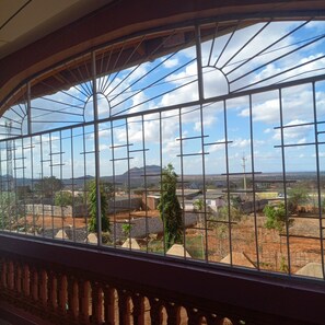 Vista a través de una ventana con barrotes, mostrando un paisaje con edificios, árboles y cielo despejado.