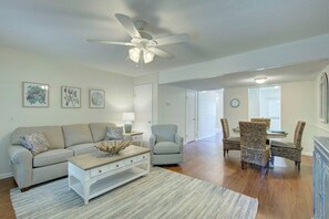 A spacious living room with a ceiling fan, a dining area with wicker chairs, and a light-colored sofa. - COMPLETELY RENOVATED! Newly furnished 2 bedroom condo in the heart of St. Simons (St. Simons Island)
