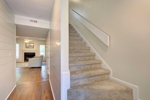 A hallway with a carpeted staircase and a fireplace in the background. - COMPLETELY RENOVATED! Newly furnished 2 bedroom condo in the heart of St. Simons (St. Simons Island)