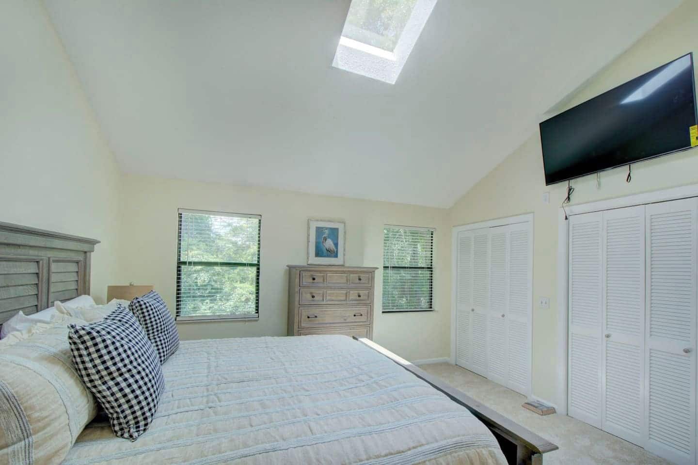 Une chambre à coucher comprenant un lit, une commode, un placard et un téléviseur fixé au mur.