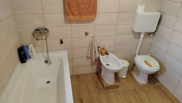 A bathroom with a bathtub, a bidet, and a toilet.