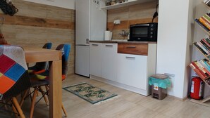 Una cocina compacta con refrigerador, microondas y gabinetes de madera.