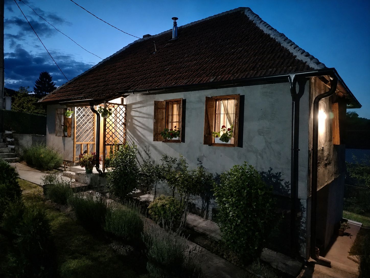 Een tweelaags huis met een schuine dak, houten luiken en een kleine tuin.