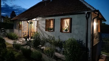 Een tweelaags huis met een schuine dak, houten luiken en een kleine tuin.