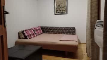 Ein kleines Zimmer mit einer Couch, einem kleinen Tisch und einem gerahmten Bild an der Wand.