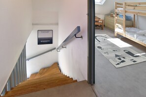 Eine Treppe führt zu einem Schlafzimmer mit einem Etagenbett, einem hölzernen Schreibtisch und einem an der Wand befestigten Schild.