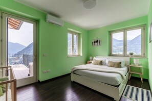 A bedroom with a bed, bedside tables, a window, and a view of mountains. - Villa Lilla (Muronico)