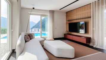 Uma sala de estar moderna com sofá, puf e televisão de tela plana presa a uma parede de painéis de madeira.