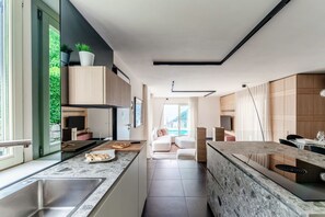 Una cocina moderna con una isla central, electrodomésticos integrados y vistas a un balcón.