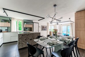 Cocina moderna con una isla central, comedor con sillas y vistas al exterior.