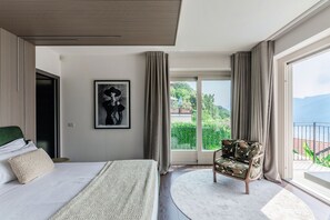 Un dormitorio moderno con una cama grande, una silla, un cuadro enmarcado y un balcón con vistas.