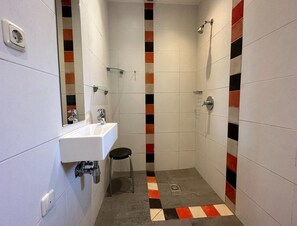 A bathroom with a white sink, a mirror, a shower, and a tiled floor with a checkered pattern. - Comfortable Heuvelland Family Escape (Gulpen)