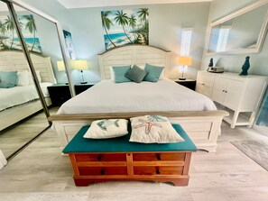 Een slaapkamer met een bed, nachtkastjes, een kaptafel en een spiegel.
