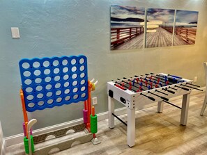 A room with a foosball table and a blue pegboard with colorful handles. - 3 min walk2 bch•Heat Pool•Bbq•100”TV•On Ocean Blvd (Fort Lauderdale)