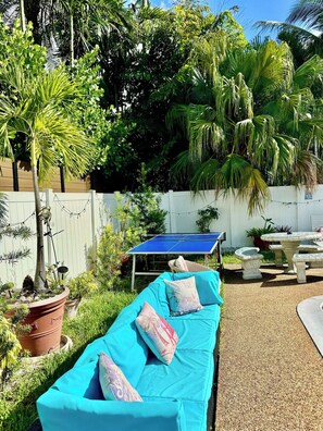 A garden area with a blue outdoor seating arrangement, a ping pong table, and various potted plants. - 3 min walk2 bch•Heat Pool•Bbq•100”TV•On Ocean Blvd (Fort Lauderdale)