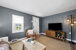 Un salon comprenant un canapé, une table basse, un téléviseur et un lampadaire.