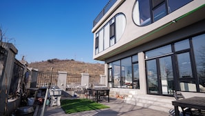 Un edificio moderno con grandes ventanales, techo plano y un patio con mobiliario exterior.